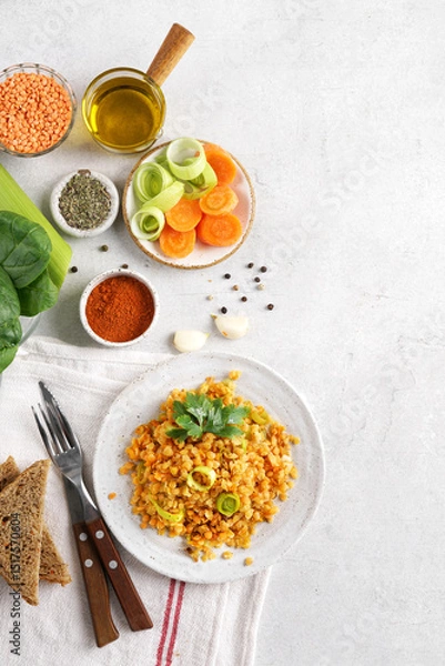 Obraz Red lentil dish with leek and carrot on the plate with ingredients nearby. Vegetarian cooking, top view, copy space