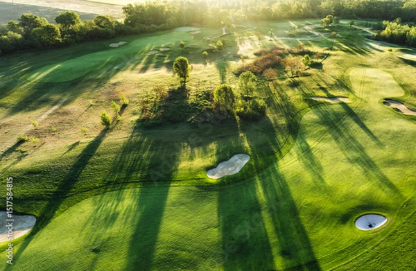 Obraz Golf course at sunset with beautiful sky and sand trap. Scenic panoramic view of golf fairway with bunker from drone