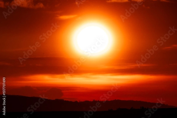 Fototapeta Close-up of the blazing sun dominating a vivid orange-red sky, creating a powerful visual of intense natural energy