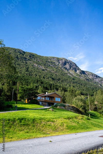Fototapeta A rural landscape in the Sunnfjord district of Western Norway, located in the Sogn og Fjordane county, with a farmhouse with large mountains behind it and unspoiled nature without people