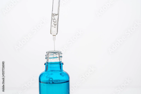 Fototapeta Dropper with a drop of hyaluronic acid and collagen serum and a blue bottle on a white background. Close-up. Copyspace.