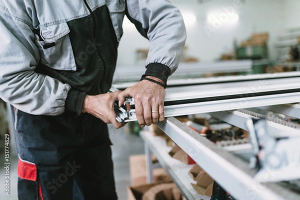 Fototapeta Factory for aluminum and PVC windows and doors production. Manual worker assembling PVC doors and windows. Selective focus. 
