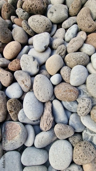 Fototapeta Madeira’s beaches are often covered in smooth pebbles made from igneous rocks like basalt and trachyte, shaped by erosion and wave action. These volcanic stones vary in color and texture, reflecting t