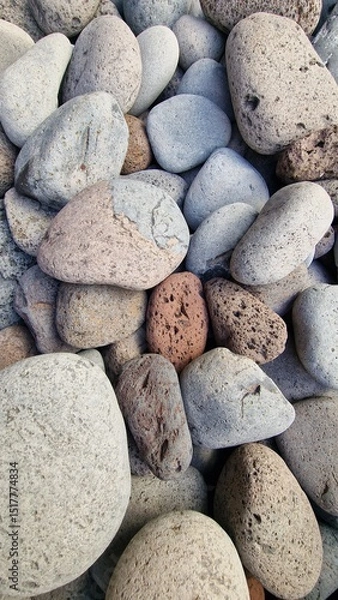 Fototapeta Madeira’s beaches are often covered in smooth pebbles made from igneous rocks like basalt and trachyte, shaped by erosion and wave action. These volcanic stones vary in color and texture, reflecting t
