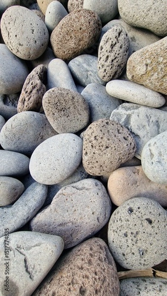 Fototapeta Madeira’s beaches are often covered in smooth pebbles made from igneous rocks like basalt and trachyte, shaped by erosion and wave action. These volcanic stones vary in color and texture, reflecting t