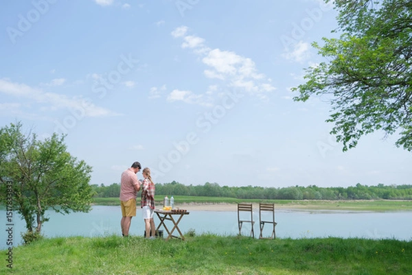 Fototapeta Family on picnic near the lake, looking at view