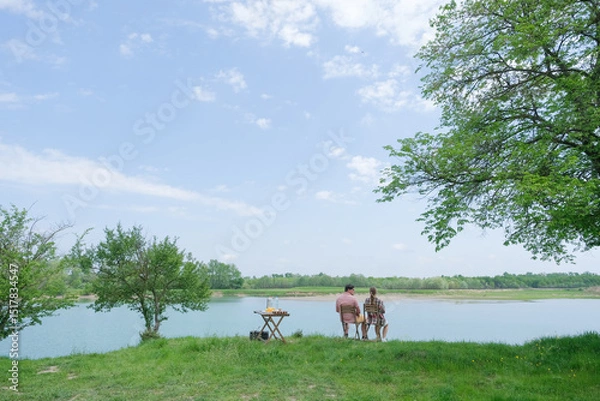 Fototapeta Family on picnic near the lake, looking at view