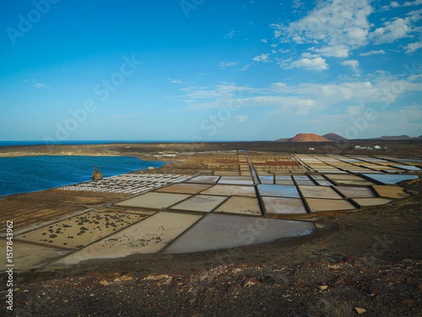 Fototapeta Rows of salt fields and evaporation ponds of Salinas de Janubio framed by volcanic coast and Atlantic Ocean. A picturesque view of the salt pans with traditional sea salt production in Lanzarote.