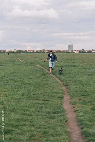 Obraz Young girl running with his dog in a large park in Berlin