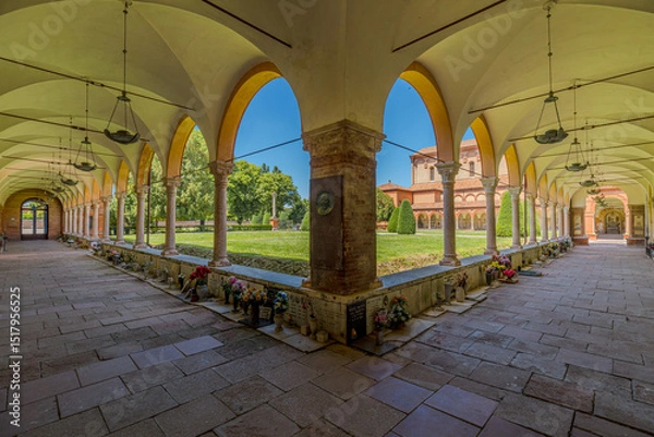 Fototapeta Ferrara, Italy - May 17, 2025: Monumental cemetery of the Charterhouse of Ferrara in Italy features a curved portico with arches and columns surrounding a green lawn under a clear blue summer sky