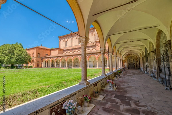 Fototapeta Ferrara, Italy - May 17, 2025: Cemetery of the Charterhouse of Ferrara with its characteristic arcades and tombs under a beautiful summer sky with lush green lawn