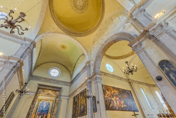 Fototapeta Ferrara, Italy - May 17, 2025: Interior of Saint Christopher church of Charterhouse of Ferrara with vaulted ceiling, crucifix, altar, paintings and wooden pulpit, creating a serene atmosphere of faith