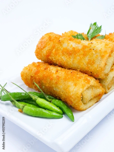 Fototapeta A plate of crispy golden vegetable risol served with green chili peppers and parsley garnish. isolated on white background. risol isolated
