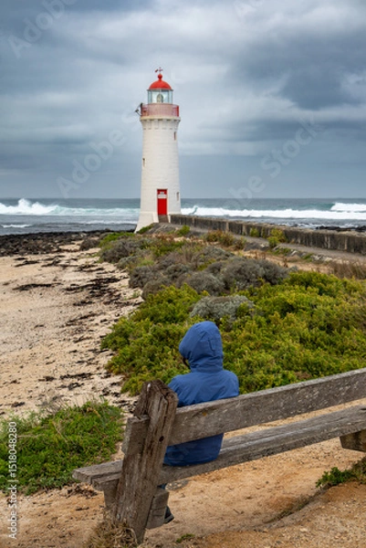 Fototapeta Person Viewing Griffiths Island Lighthouse from Wooden Bench on Coastal Path