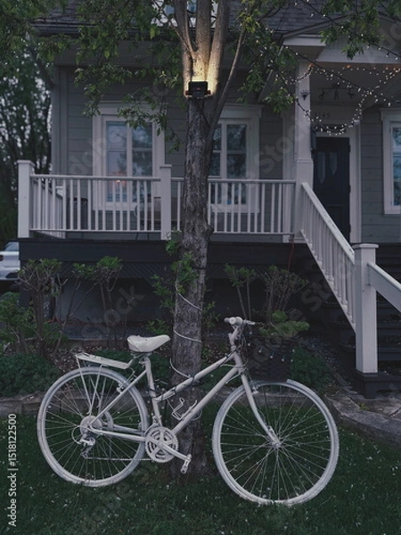 Fototapeta Un vélo devant une maison avec une lampe le soir. Un vélo fantôme devant une maison.