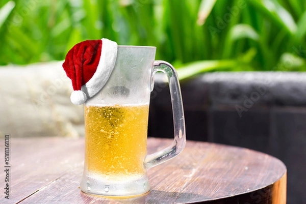 Obraz Santa Claus Hat on glass of beer on table. Christmas and New Year celebration