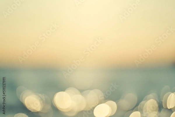 Obraz softly blurred seascape at sunset, featuring golden light reflections dancing across the water in a warm, serene atmosphere.
