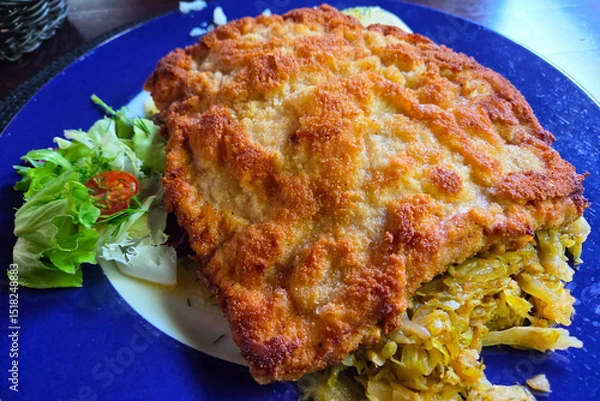 Fototapeta Crispy Breaded Schnitzel with Fresh Salad on Blue Plate for Culinary Presentation