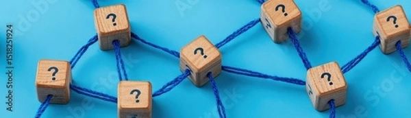 Obraz Wooden blocks with question marks are connected by blue strings, symbolizing a network of questions or uncertainty on a blue background.