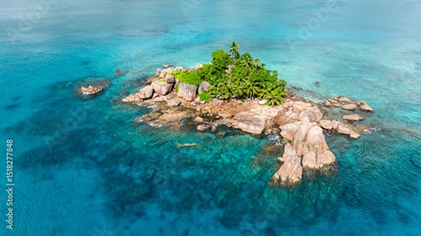 Fototapeta An island surrounded by turquoise ocean waters with prominent granite formations and lush greenery. Seychelles, Praslin.