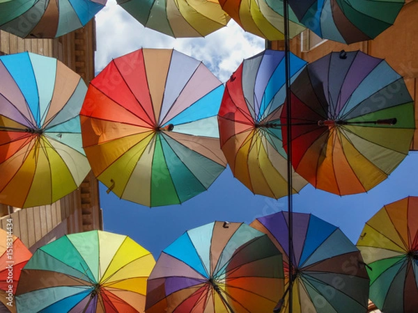 Fototapeta Colorful umbrellas hanging above a narrow street on a sunny day