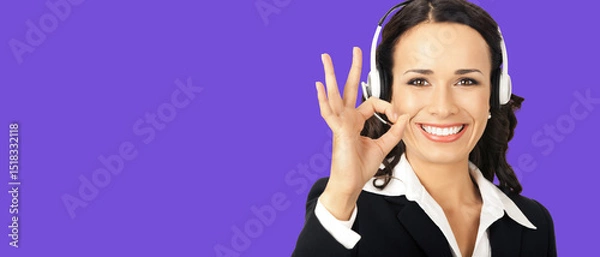 Fototapeta Portrait image of happy smile corporate customer support callcenter phone operator in headset show pointing okay ok hand sign gesture, isolate violet purple background with free ad slogan text space
