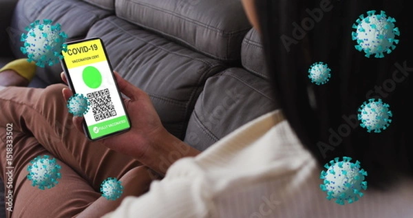 Obraz Image of covid 19 cells over woman relaxing at home with digital covid passport on phone screen