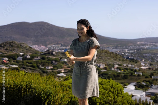 Fototapeta Gold confetti popper is resting among shrubs on hillside overlooking coastal village and horizon