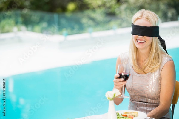 Obraz Glass of red wine resting on tabletop beside salad plate and white flower near turquoise pool