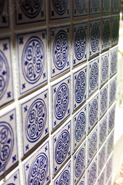 Fototapeta A close up of a blue and white mosiac patterned tile on a wall