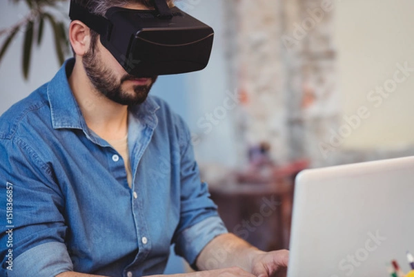 Obraz VR headset resting on laptop keyboard inside loft-style workspace with brick wall and potted plant
