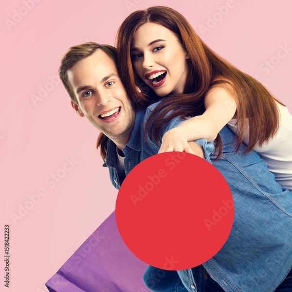 Fototapeta Holiday sales actions, rebates offers, price discounts, ad concept image - happy expressive young couple man and woman with shopping bag, hold red сircle sign board. Isolated pink background. Square