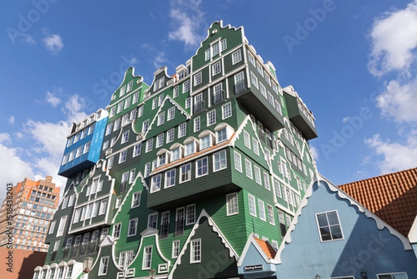 Obraz Unique and colorful hotel building resembling stacked traditional Dutch houses in Zaandam the Netherlands, set against a bright blue sky, showcasing innovative architecture.