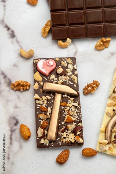 Obraz Novel artisanal white and dark chocolate bars with golden chocolates in the shape of tools and nuts glued on, ideal for gifts.