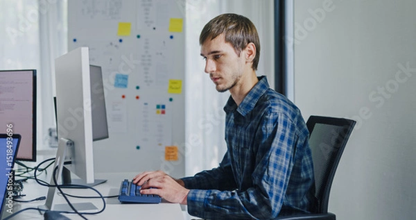 Fototapeta Young adult male freelance developer typing write prompt AI bot app program nomad terminal with coding at office. Artificial intelligence dashboard, robotics, user interface, machine learning concept.