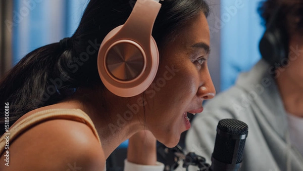 Fototapeta Close-up Young happy Asia couple wear headphone sit on desk online live streaming football live score watch soccer sport game on laptop use microphone talk with follower small studio in home at night.