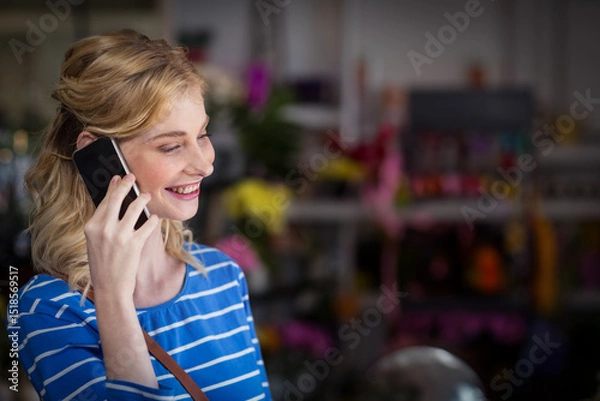 Obraz Smartphone resting on brown purse strap amid colorful cut flowers and potted plants in florist shop