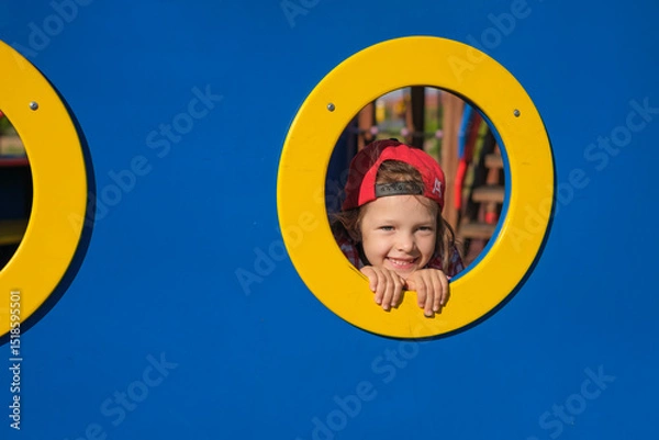 Obraz Funny girl peeks through a hole in the playground