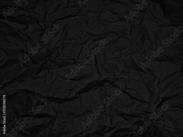 Fototapeta Crinkled black textured surface with folds and creases creating an abstract pattern. No text present. Dark and moody atmosphere with irregular shapes and shadows on the material