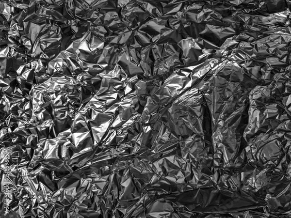 Fototapeta Crinkled metallic surface with irregular, shiny textures creating abstract shapes and patterns. The play of light and shadow enhances the three-dimensional appearance