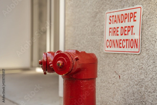 Obraz A red fire hydrant stands next to a wall-mounted emergency sign. The image emphasizes urban safety infrastructure in New York City.