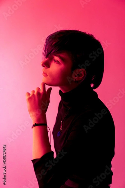 Obraz A young woman with short hair is standing in front of a pink background