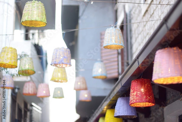 Fototapeta Decorative multicolor wicker lamps are hanging under the street in a small European town