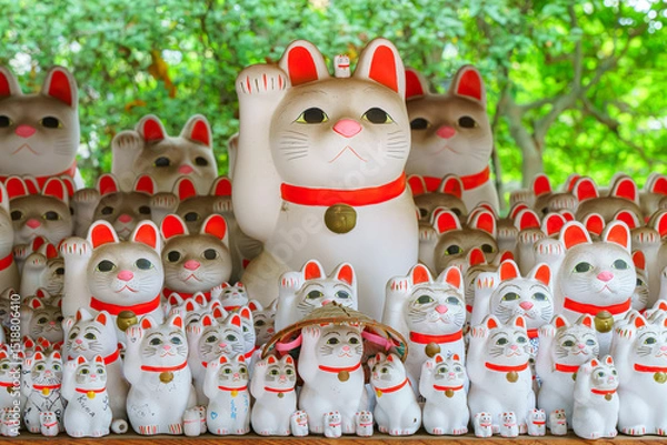 Fototapeta Tokyo, Japan - Sep 30 2024, A close-up view of many multi-sized white beckoning cat figure of Maneki neko with red ears and noses displayed at Gotokuji Temple, without people, at daytime, Tokyo, Japan