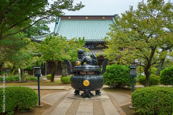 Fototapeta Tokyo, Japan - Sep 30 2024, Panoramic view of the bronze incense burner decorated with a lion statue, surrounded by trees, on road to Gotokuji Temple, without people, at daytime, Tokyo, Japan