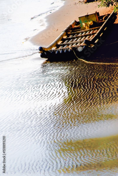 Obraz A bamboo raft rests on a sandy shore with rippling water, captured at sunset on October 7, 2012, in Miaoli County, Taiwan.