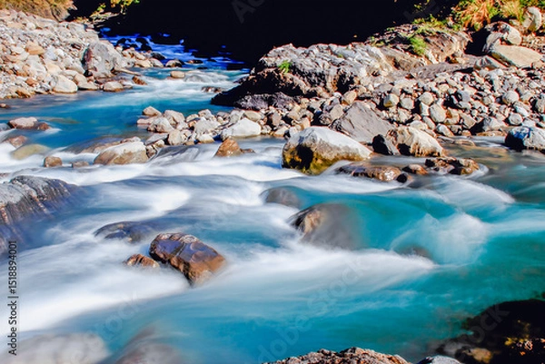 Obraz A serene winter stream flows through a rocky forest in Taiwan, with clear blue water and smooth rocks under sunlight.