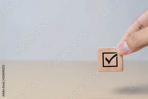 Obraz Business and quality assurance concept. Hand arranging checkmark icon on wooden block representing document approval and project validation