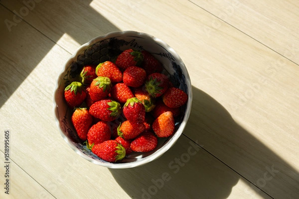 Fototapeta Fresh ripe strawberries with vibrant red hues in a bowl with natural light. Red summer fruit background.