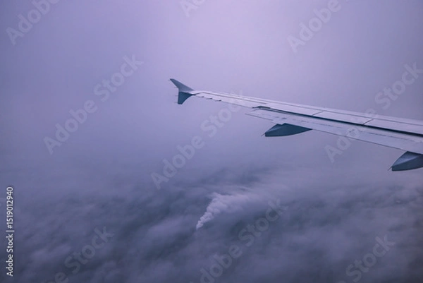 Fototapeta Airplane flying over color sky clouds during scenic sunset or sunrise cloudscape, view from plane window of wing turbines and horizon